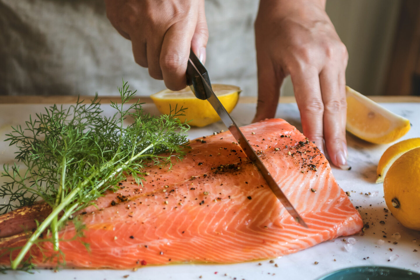 chef cuts up salmon seasoned with dill salt and pepper