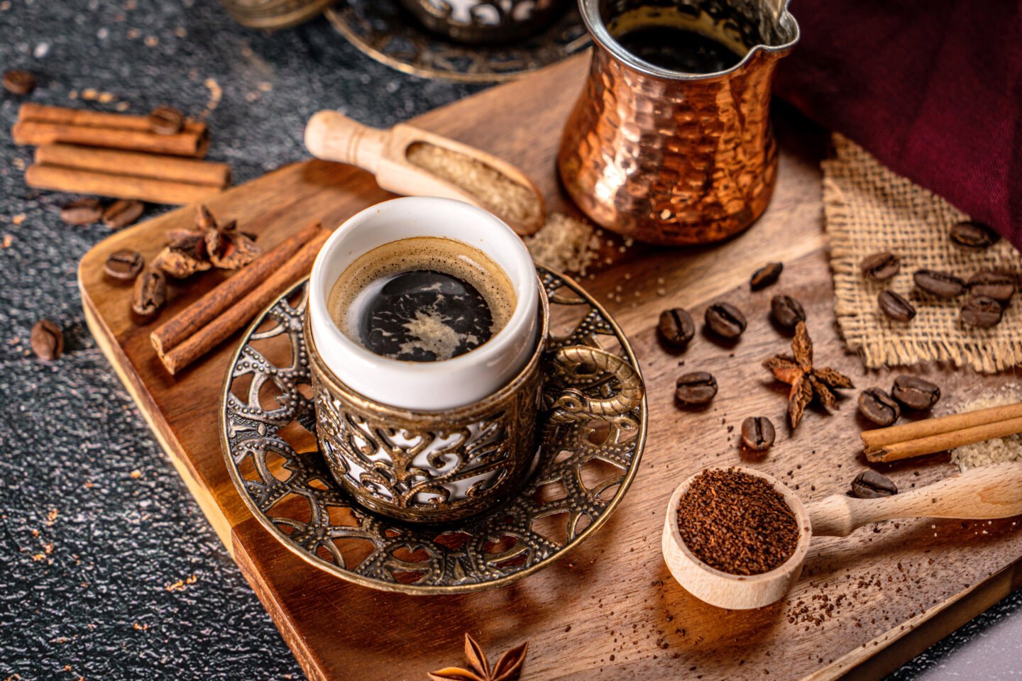 cup-of-turkish-coffee-on-black-background-with-spices-coffee-beans-and-sand-coffee-pot