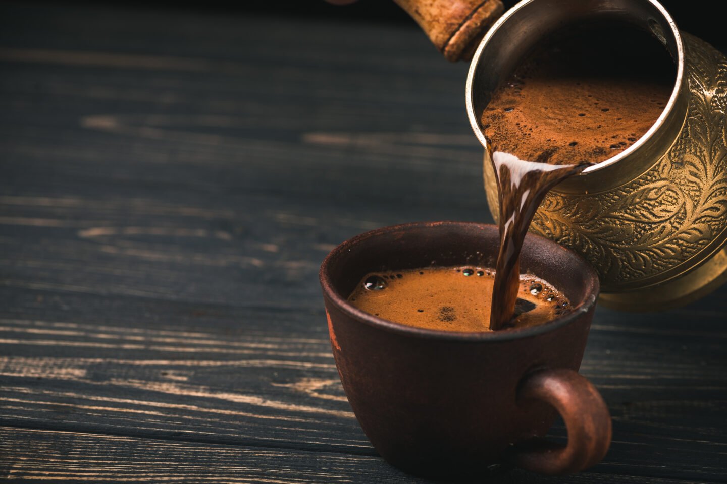 pouring-turkish-coffee-into-vintage-cup-on-wooden-background
