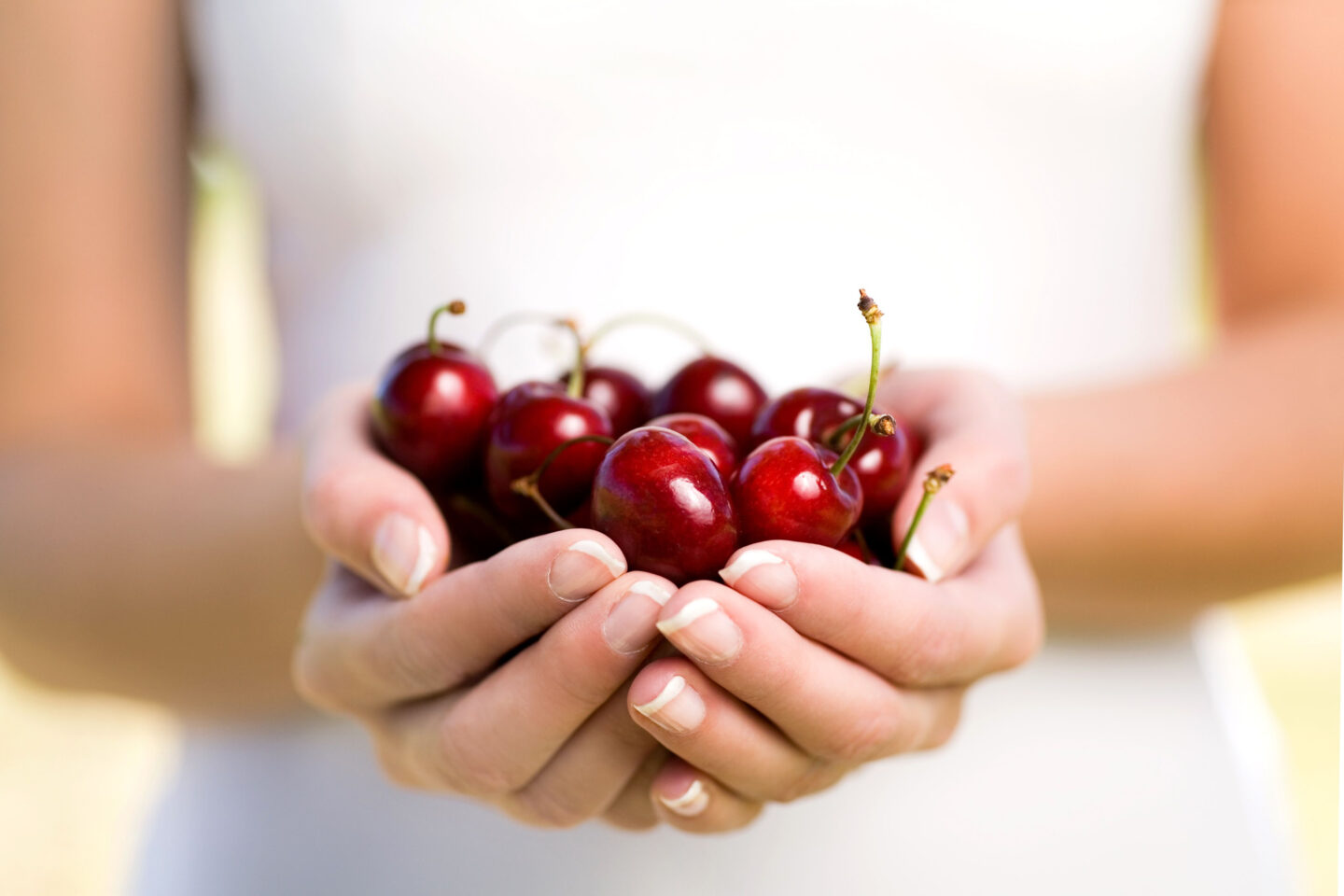 woman holds a handful of cherries