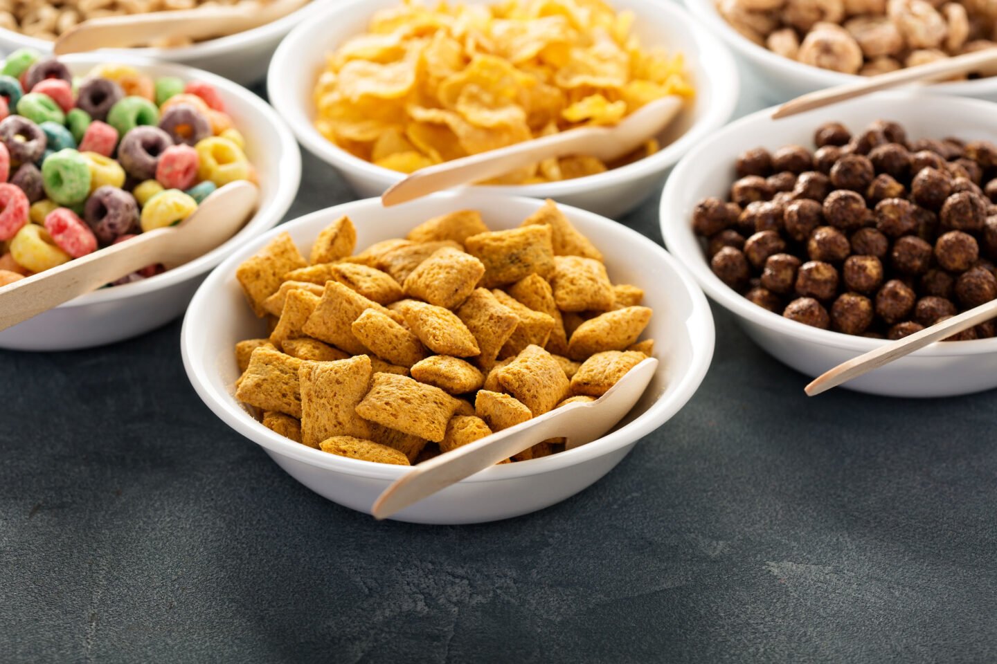 different cereals in white bowls with spoons