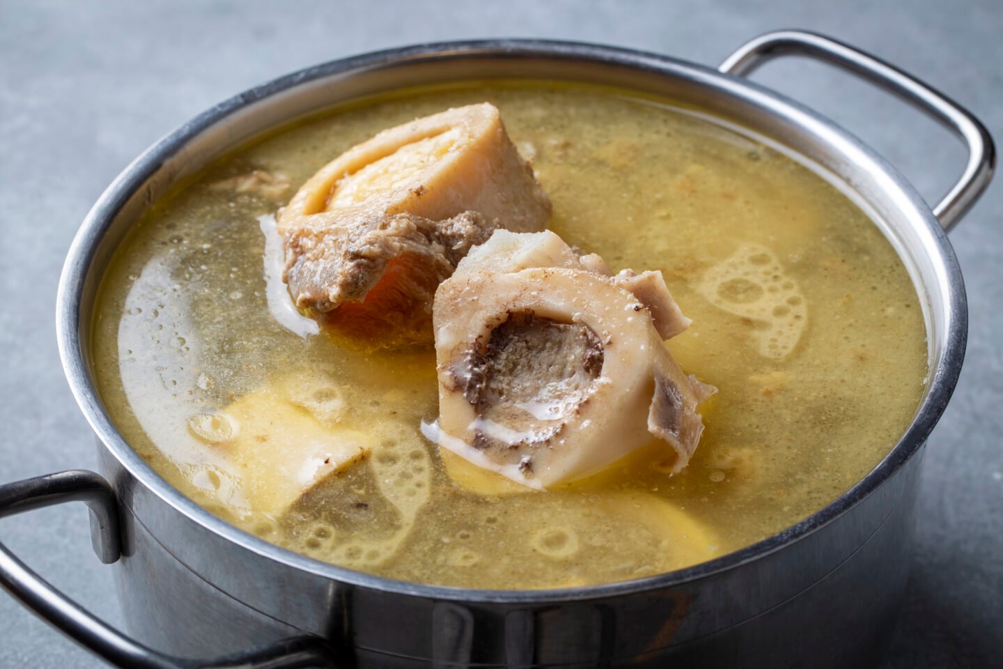 Boiled bone and broth. Homemade beef bone broth is cooked in a pot.