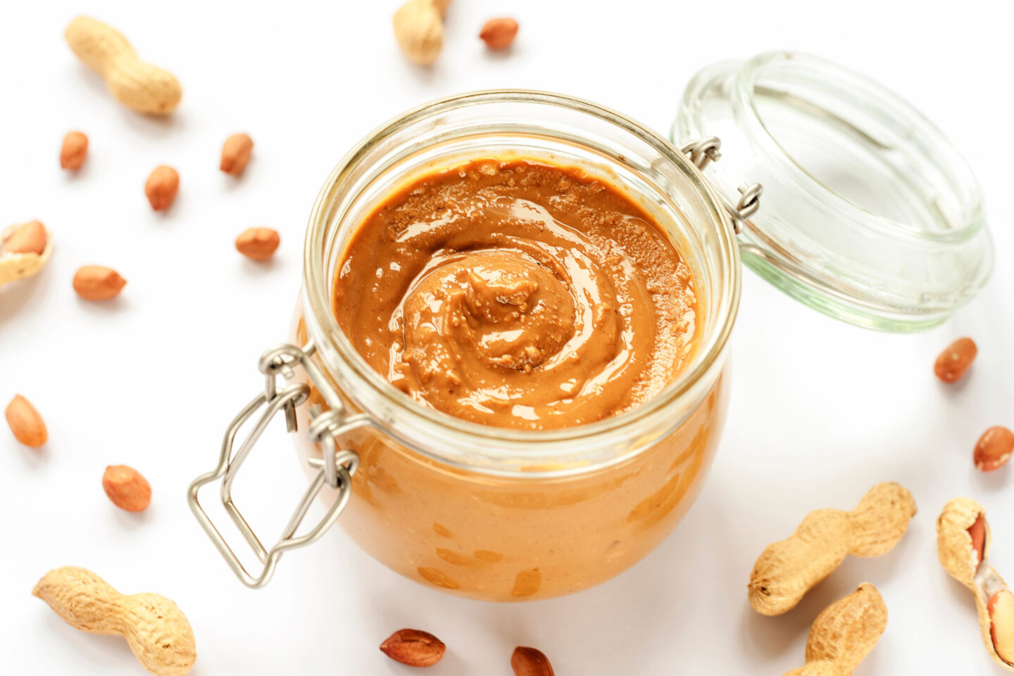 peanut butter in a jar and scattered peanuts