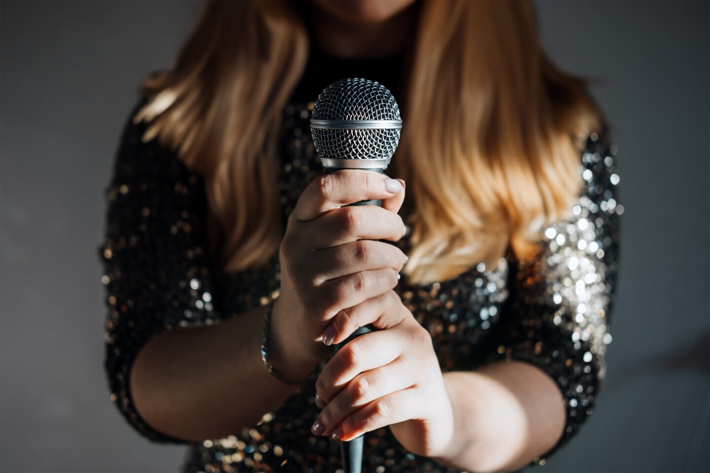 faceless woman holding microphone in sparkly dress
