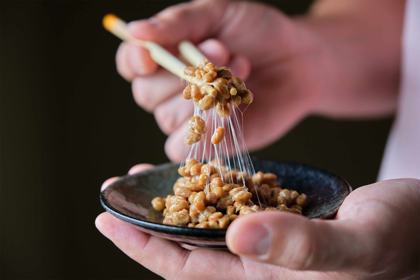 hand holding chopsticks with natto fermented soy beans